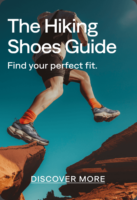 A hiker jumping between red rock formations wearing Merrell hiking shoes.